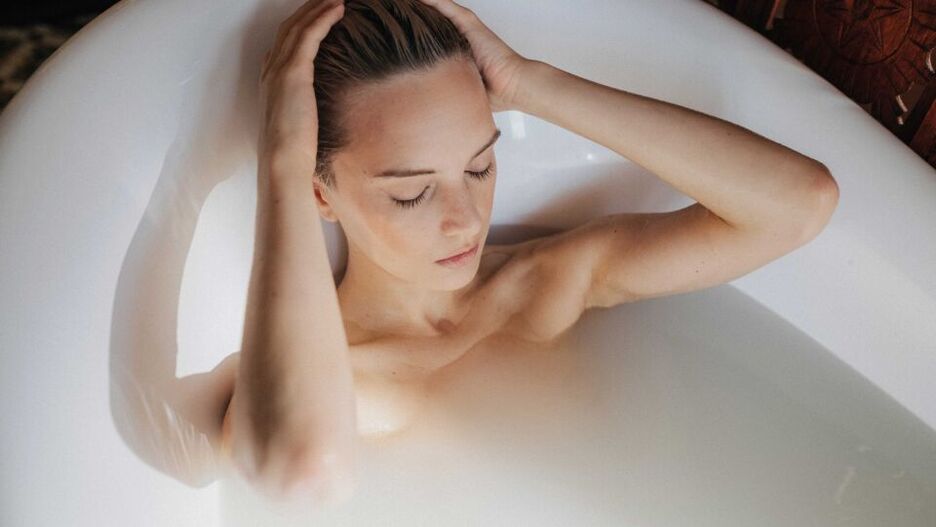 Eine junge Frau entspannt in der Badewanne, um ihre trockene Haut zu pflegen.