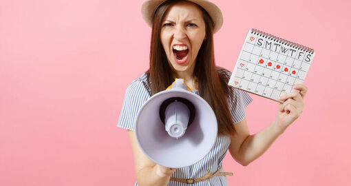 Eine Frau hält einen Kalender und ein Megafon in der Hand. Sie schreit etwas in das Megafon.