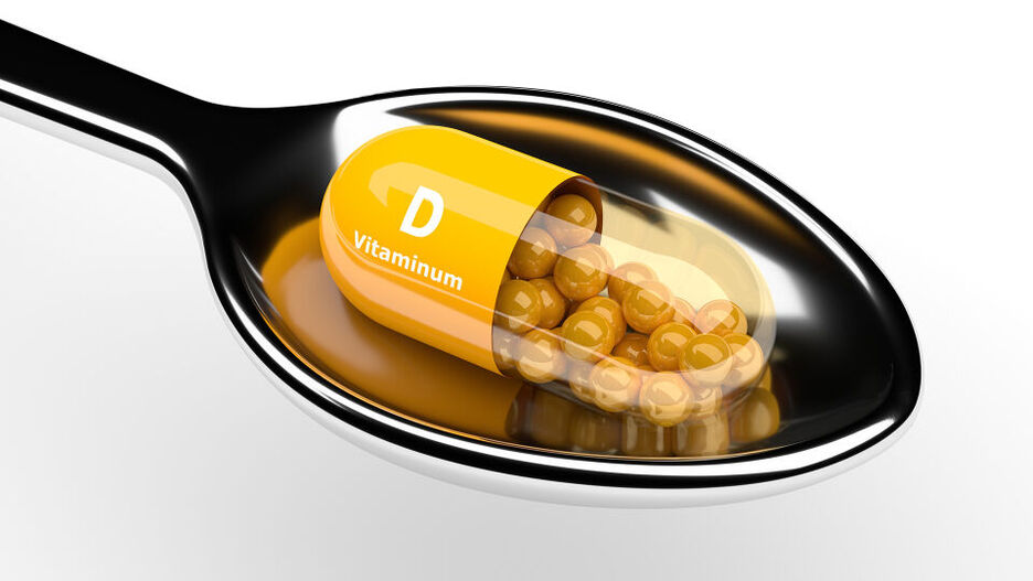 Eine Kapsel Vitamin D liegt auf einem Löffel. 